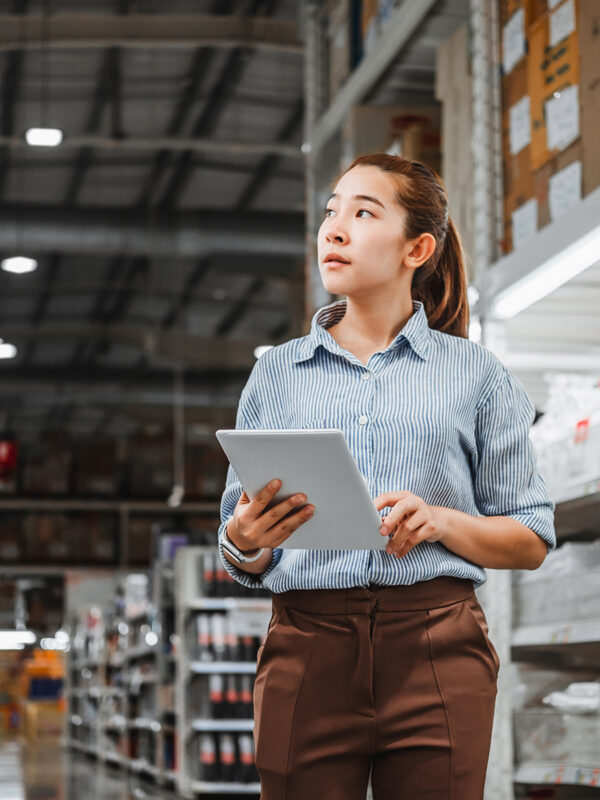 Asian woman worker working with digital tablet checking boxes Logistic import and export supplies packages in Warehouse , Logistics concept